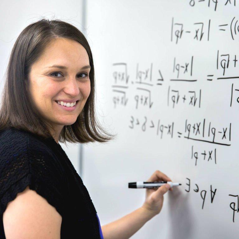 Photo of Professor writing math equation on board.